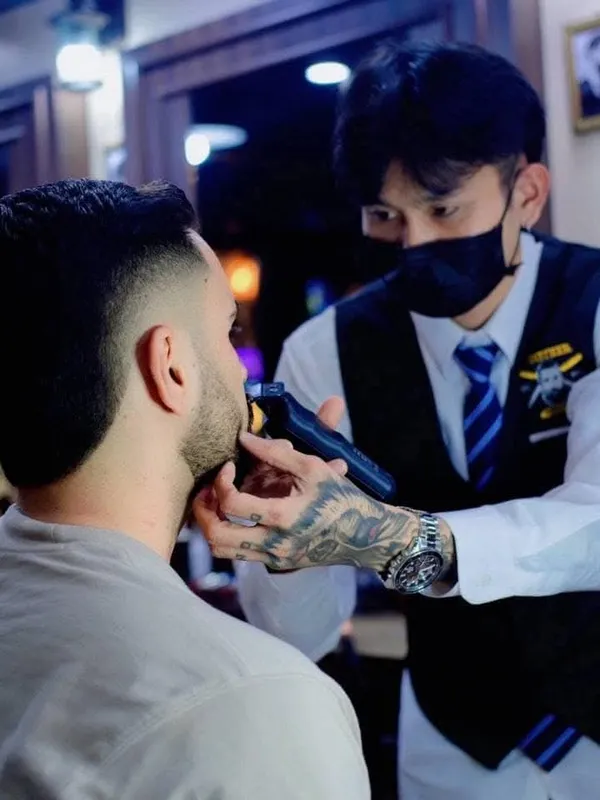 Barber trimming a beard line with clippers