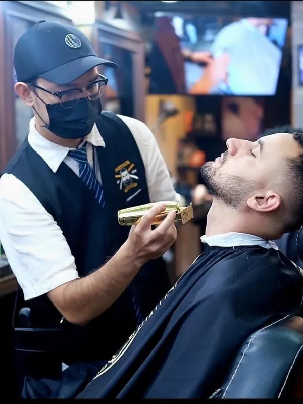 Barber finishing a cut with a gold trimmer