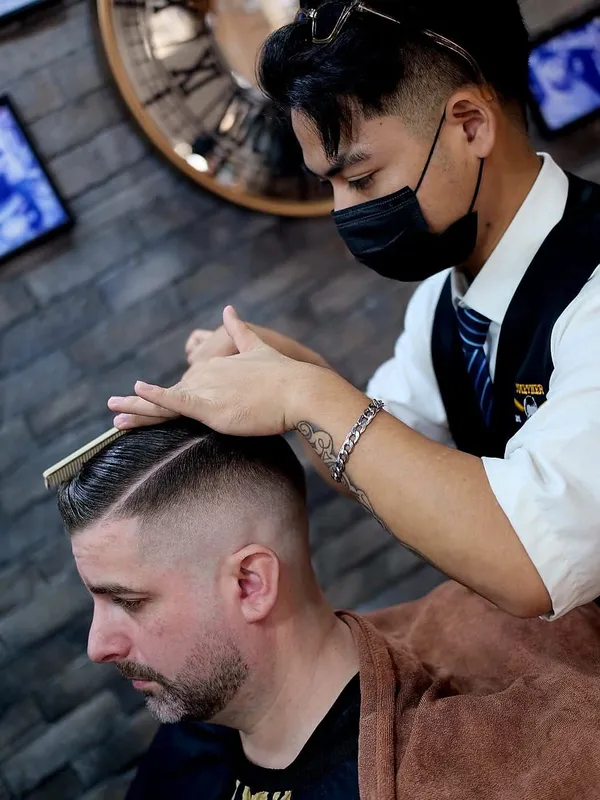 Barber combing a side part before finishing
