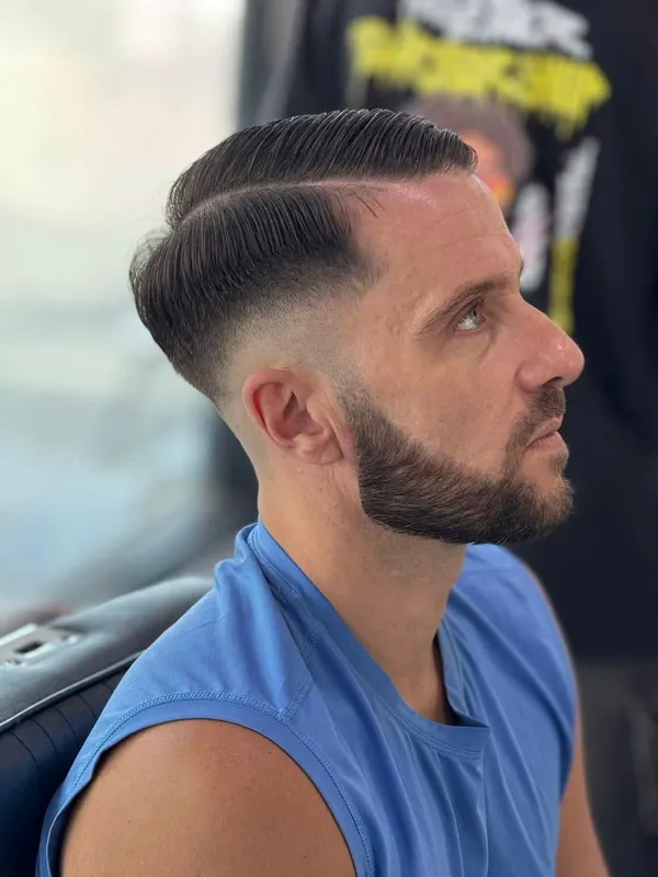 Slick side part with a beard fade